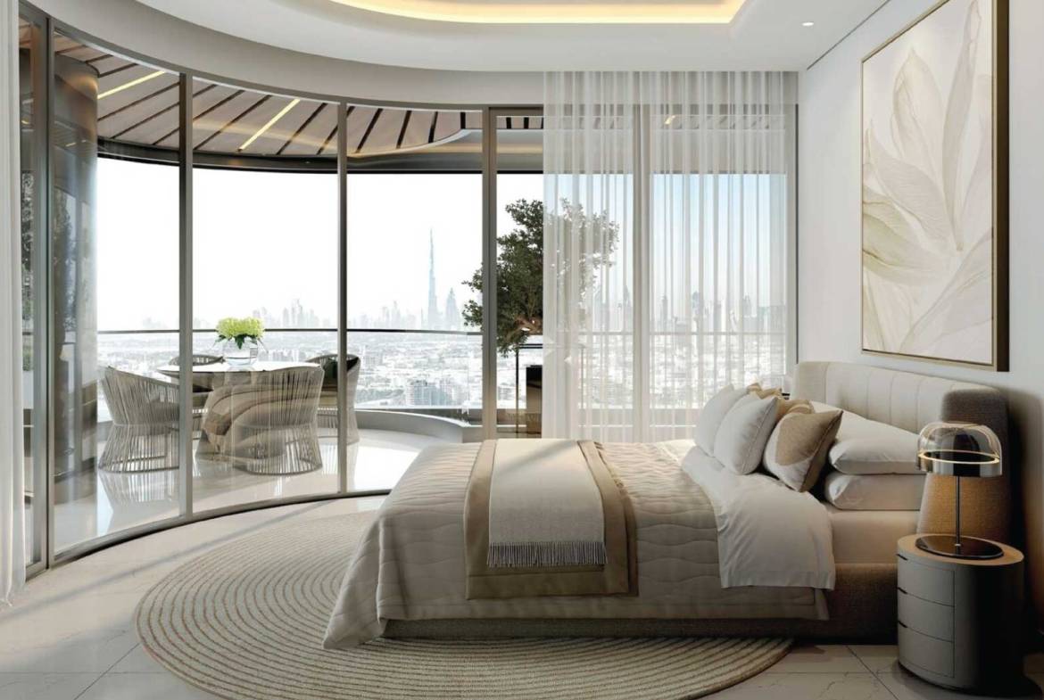 Elegant bedroom with curved glass wall, balcony seating, and panoramic Dubai skyline view