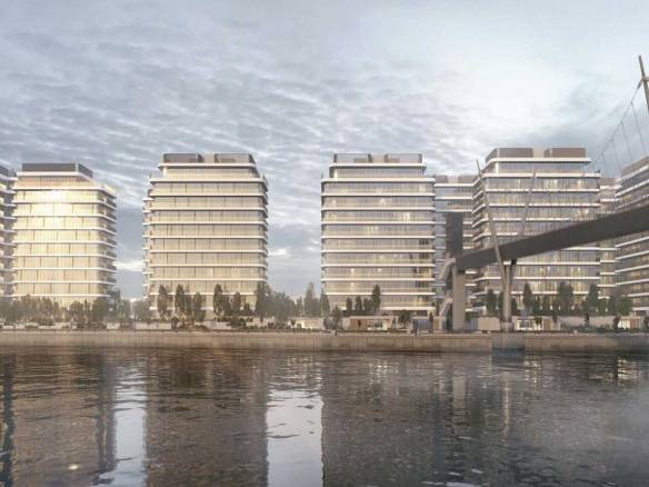 Modern waterfront residential towers with glass facades and pedestrian bridge over calm water