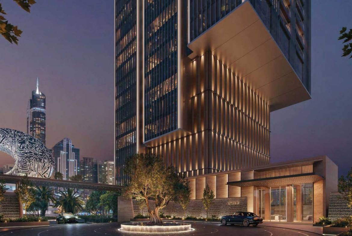 Night view of illuminated skyscraper entrance with luxury car and city skyline backdrop