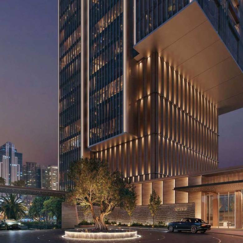 Night view of illuminated skyscraper entrance with luxury car and city skyline backdrop