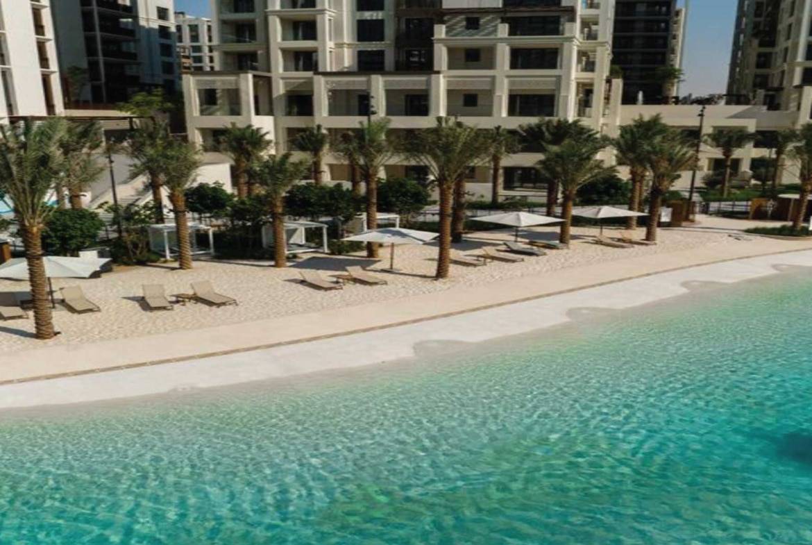 Private sandy beach with palm trees and sun loungers in luxury residential complex