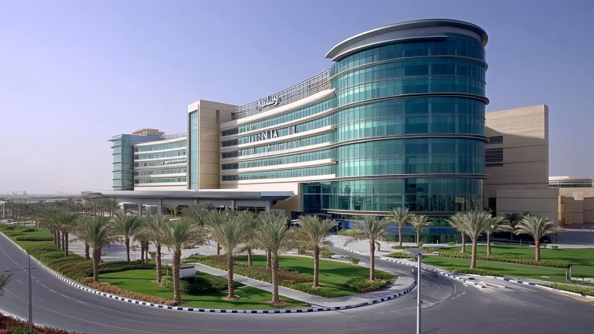 Modern hospital building in Dubai with glass façade and palm trees