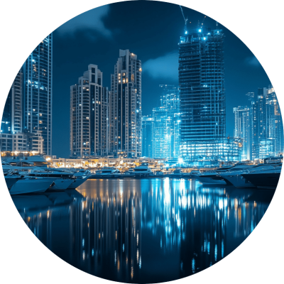City skyline illuminated at night, with boats gently floating on the water in the foreground